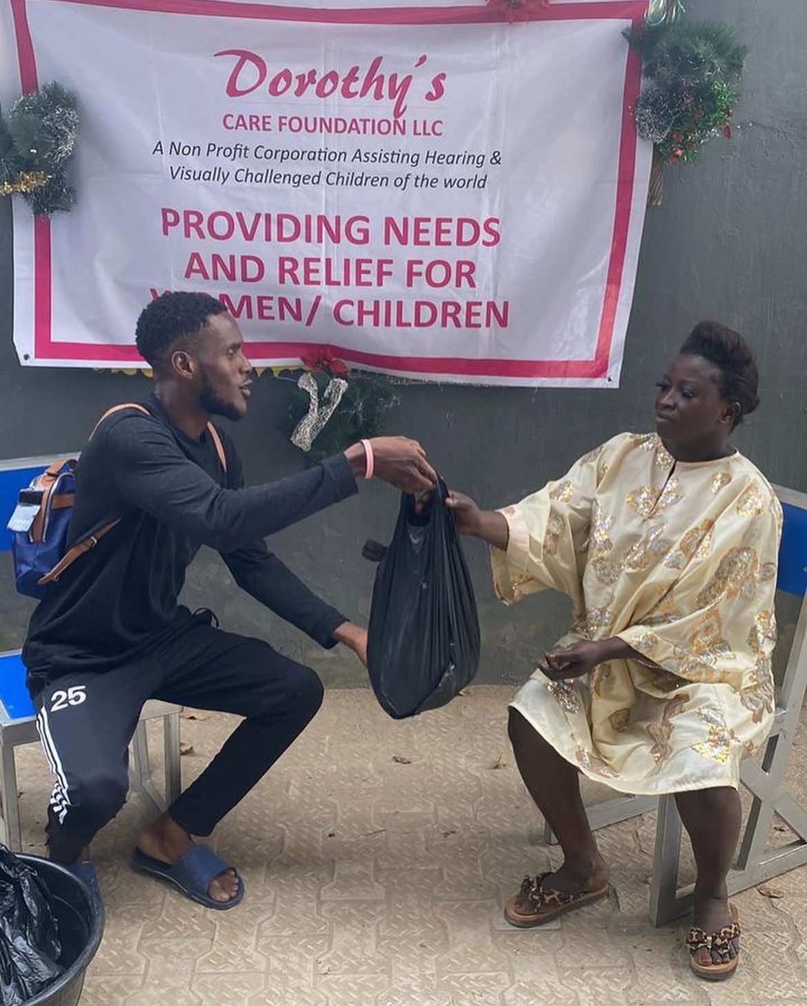 A volunteer hands a bag of supplies to a recipient at a Dorothy's Care Foundation distribution event.